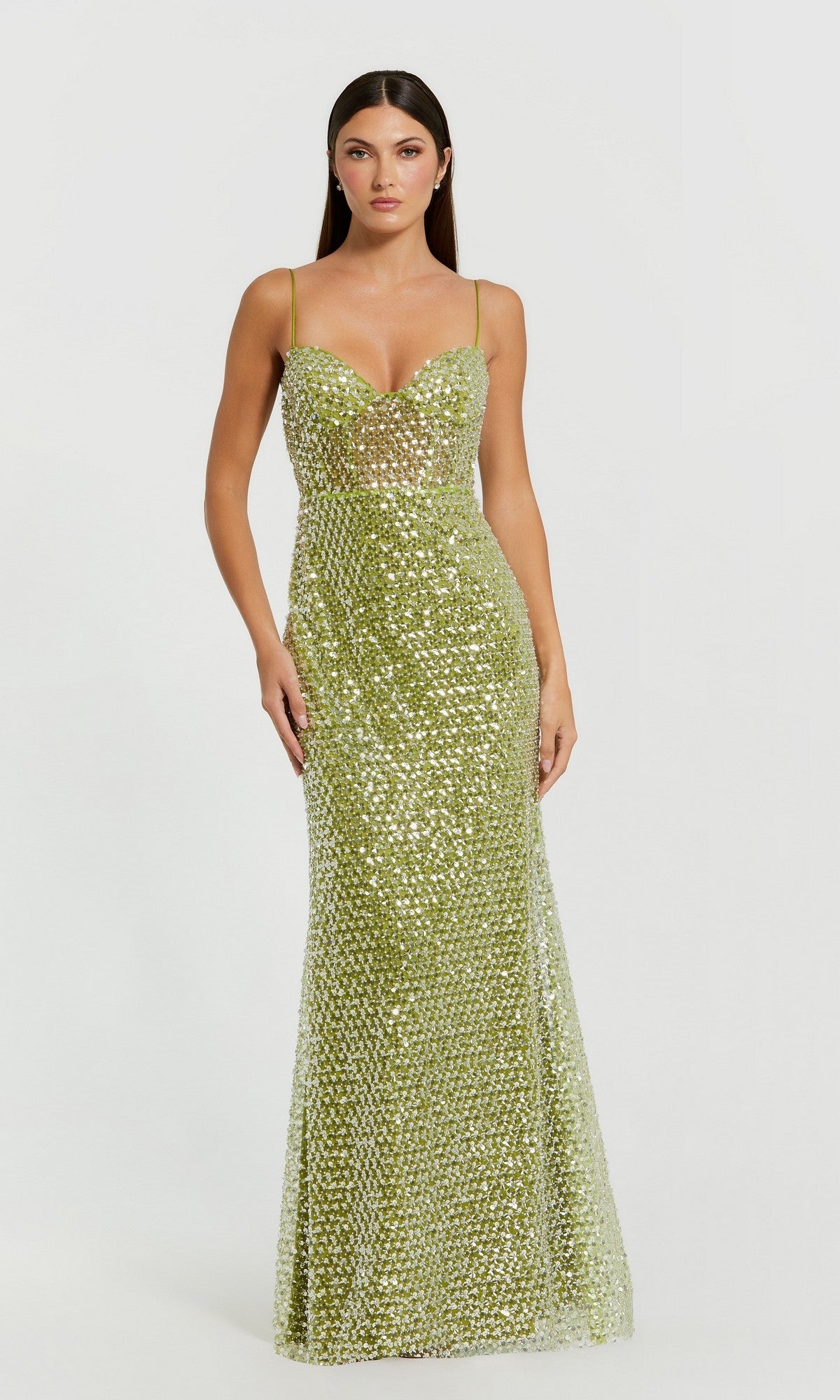 A woman wearing the Mac Duggal 68895 long formal dress in apple green, featuring shimmering sequins and spaghetti straps, stands against a plain white background.